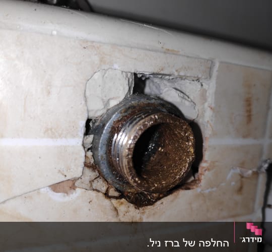 צינור מתכת חלוד בקיר עם חיבור שבור